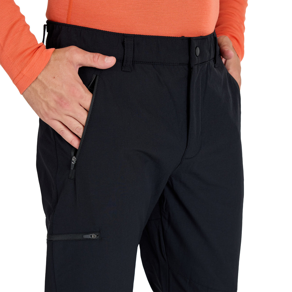 Mann mit einer schwarzen Merino Outdoorhose mit schwarzen Reißverschlüssen.