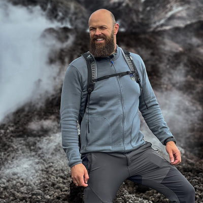 Mann mit Bart beim Wandern in den Bergen mit Merinojacke