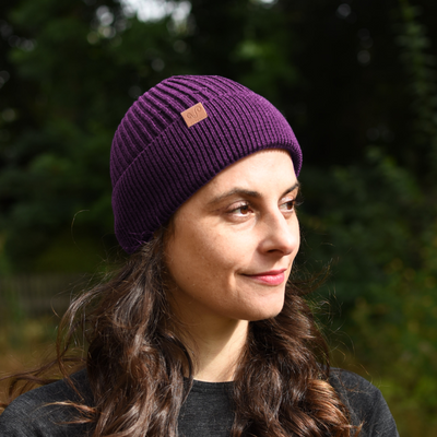 Frau mit einer violett farbenen Merino Mütze 