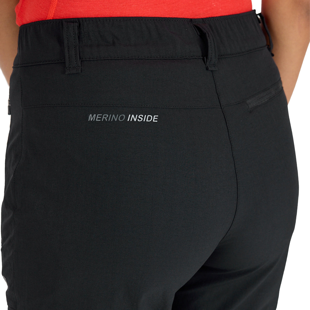 Hinterer Bereich einer schwarzen Merino Outdoorhose für Damen mit Zip Off Funktion und der Aufschrift Merino Inside. 