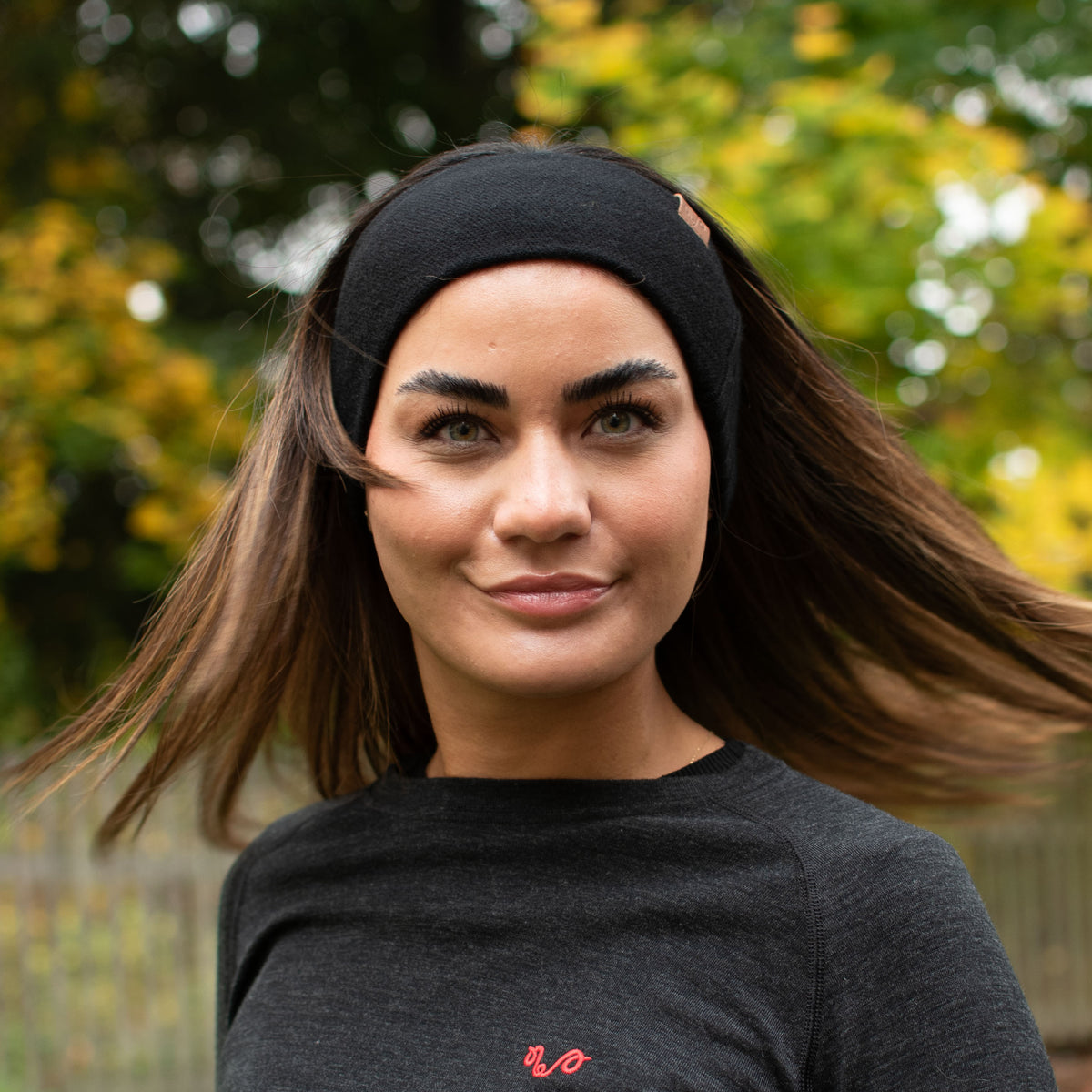 Eine Dame mit einem anthrazit Farben Oberteil und einem schwarzen Stirnband beides aus Merinowolle. 