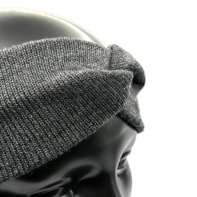 Aus den Nähe ein Stirnband aus Merino in Anthrazit auf einem Puppenkopf das den Knoten zeigt