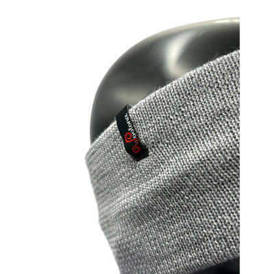 Ein Puppenkopf aus der nähe das ein Stirnband aus Merino in Grau trägt mit dem Woolona Logo