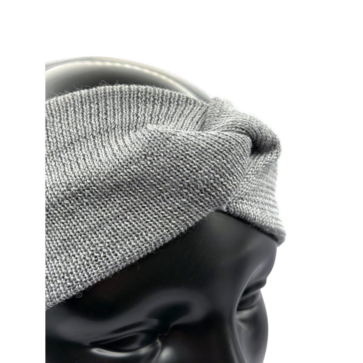 Aus den Nähe ein Stirnband aus Merino in Grau auf einem Puppenkopf das den Knoten zeigt