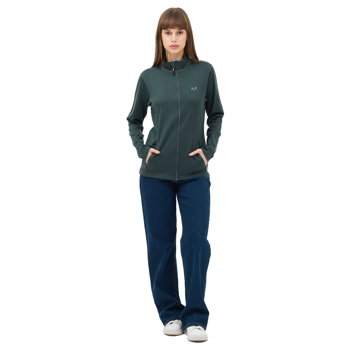 Frau mit  langen braunen Haaren, trägt einen grünen Midlayer und blaue Jeans.