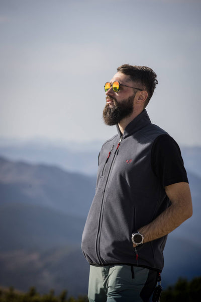 Ein Mann mit Sonnenbrille trägt eine Merinoweste und er blickt in die Ferne