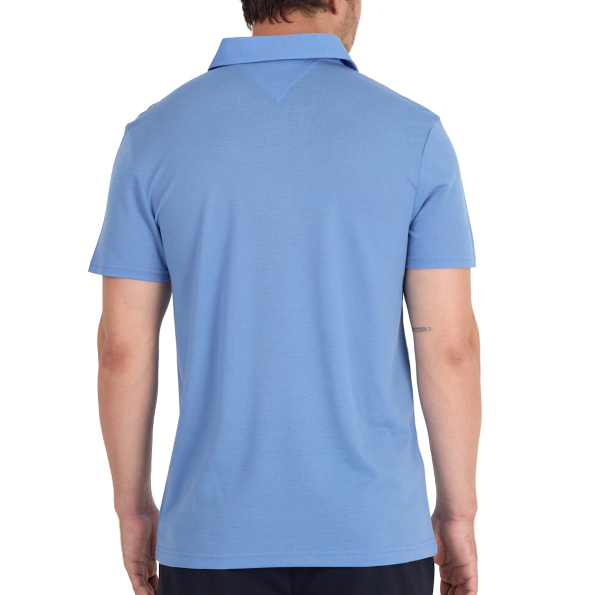 Ein Mann trägt ein blaues Merino Poloshirt im Pique Style von hinten fotografiert. 